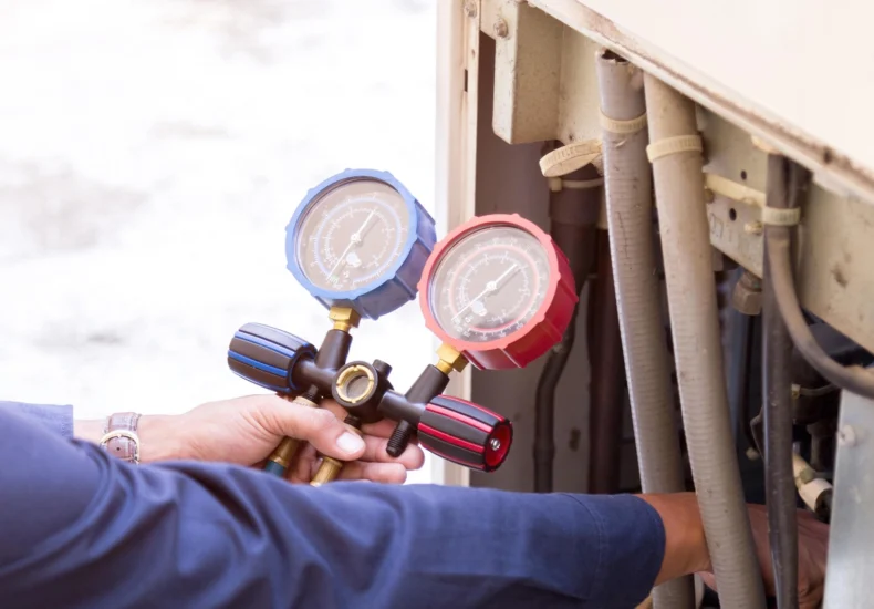 Technician using a manifold gauge set to check pressure in an air conditioning unit.